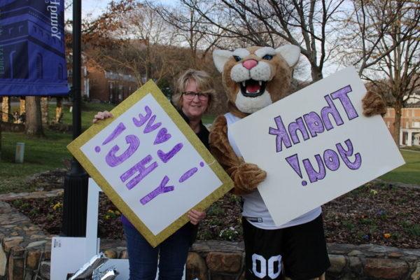 a person holding signs with a mascot